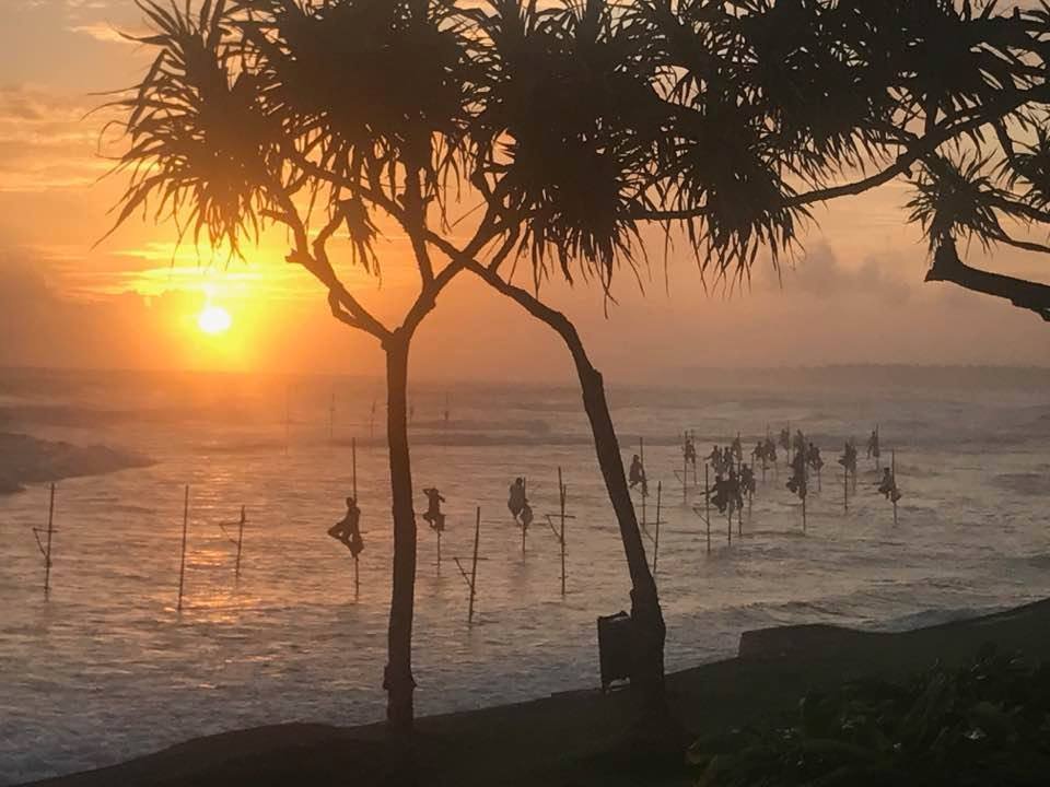 Traditional Sri Lankan stilt fishermen silhouetted on their poles in the sea at sunset near Ko Lake Villa, Ahangama